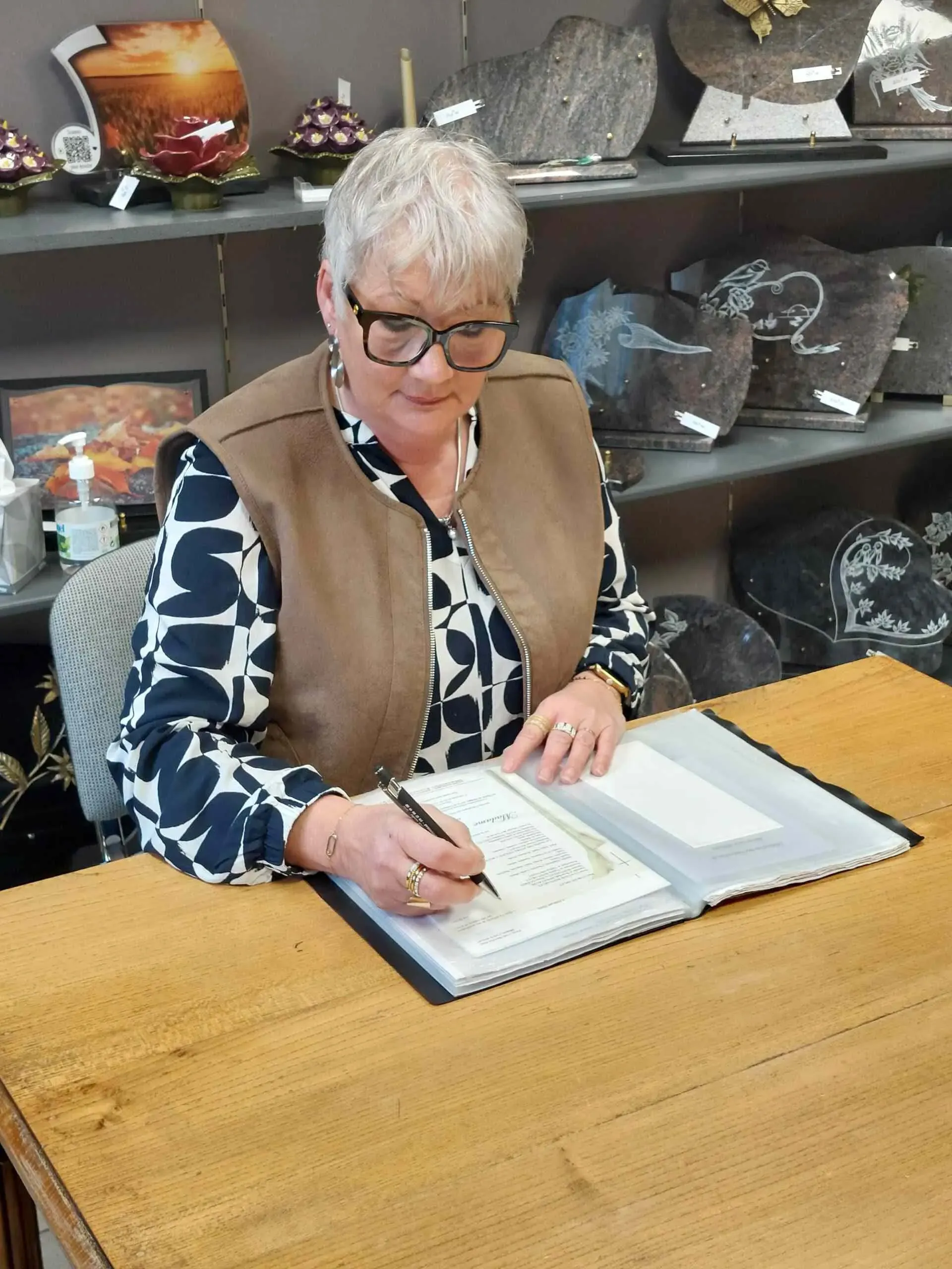 Conseillère funéraire remplissant un registre de condoléances en boutique.